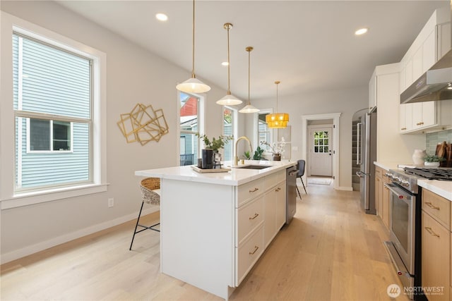 157 26th Ave, Seattle, WA 98122 - kitchen with appliances with stainless steel finishes, wall chimney exhaust hood, light wood-type flooring, an island with sink, and recessed lighting
