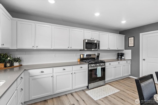 1120 15th Ave, Sultan, WA 98294 - kitchen with appliances with stainless steel finishes, white cabinetry, decorative backsplash, light wood-style flooring, and recessed lighting