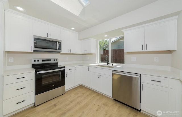 9621 1st Ave SE, Everett, WA 98208 - kitchen featuring appliances with stainless steel finishes, a skylight, light wood-style floors, white cabinets, and light countertops