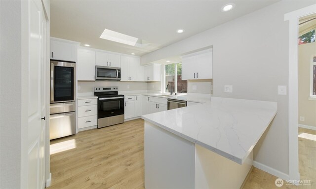 9621 1st Ave SE, Everett, WA 98208 - kitchen with stainless steel appliances, a skylight, light wood-style flooring, a peninsula, and recessed lighting
