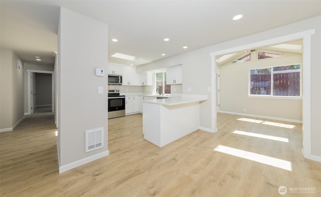 9621 1st Ave SE, Everett, WA 98208 - kitchen with stainless steel appliances, white cabinets, a peninsula, light countertops, and light wood-style floors