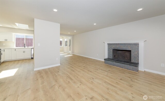 9621 1st Ave SE, Everett, WA 98208 - unfurnished living room with recessed lighting, light wood-type flooring, a fireplace, and a skylight