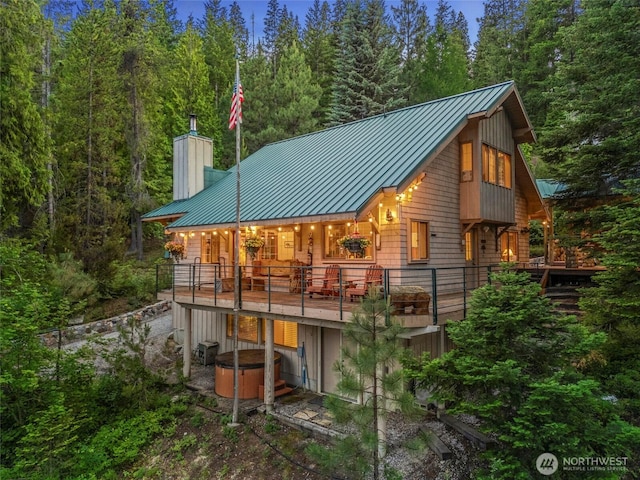 2290 Riffle Dr, Leavenworth, WA 98826 - back of house featuring a standing seam roof, a hot tub, a metal roof, and a chimney
