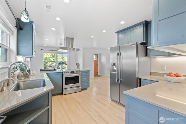 8315 24th Ave NW, Seattle, WA 98117 - kitchen with appliances with stainless steel finishes, wall chimney exhaust hood, light countertops, recessed lighting, and light wood-style flooring