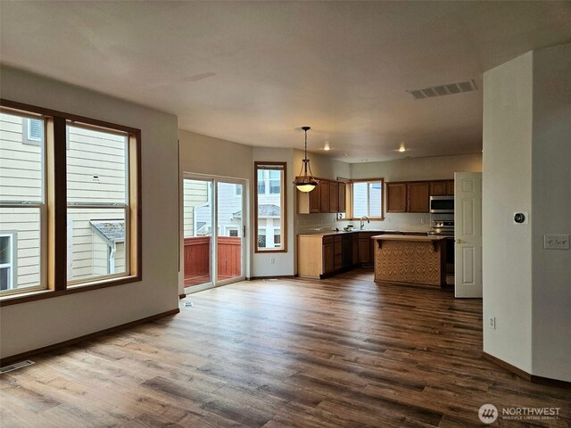 741 G St SW, Tumwater, WA 98512 - kitchen featuring stainless steel microwave, dark wood-style floors, a kitchen island, and hanging light fixtures