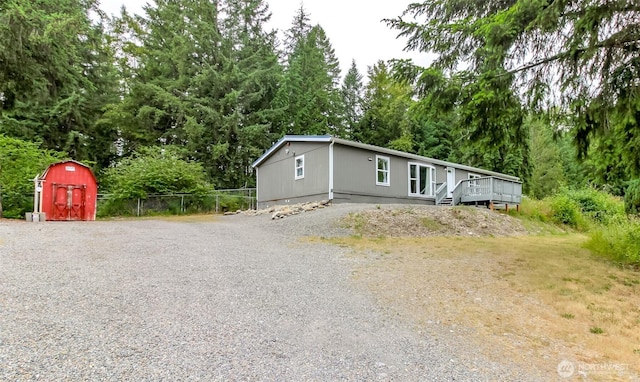 3010 248th Street Ct E, Spanaway, WA 98387 - manufactured / mobile home with a deck, a shed, gravel driveway, and view of wooded area