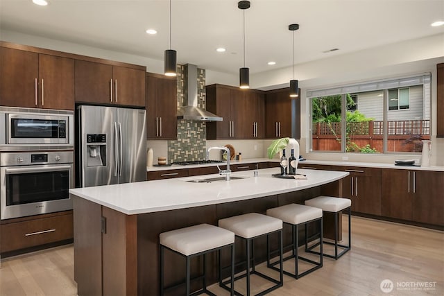10637 128th Ave NE, Kirkland, WA 98033 - kitchen with appliances with stainless steel finishes, wall chimney exhaust hood, a breakfast bar, light countertops, and recessed lighting