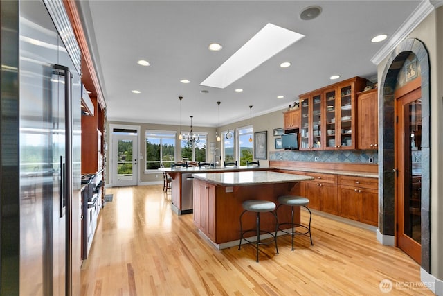60 Marigold Dr, Bellingham, WA 98229 - kitchen featuring appliances with stainless steel finishes, brown cabinetry, a kitchen bar, a skylight, and light wood-style floors