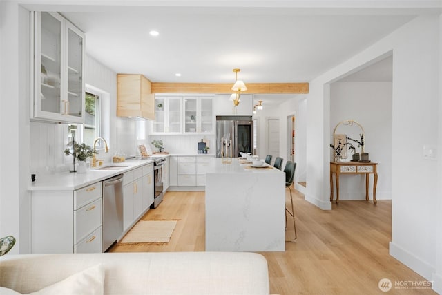 4658 N Defiance St, Tacoma, WA 98407 - kitchen with appliances with stainless steel finishes, a kitchen island, light wood finished floors, light countertops, and a breakfast bar area