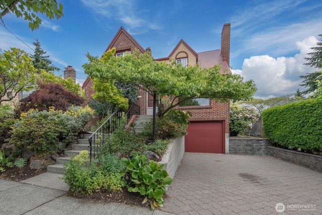 7310 10th Ave NW, Seattle, WA 98117 - tudor home with a garage, decorative driveway, brick siding, stairs, and a chimney