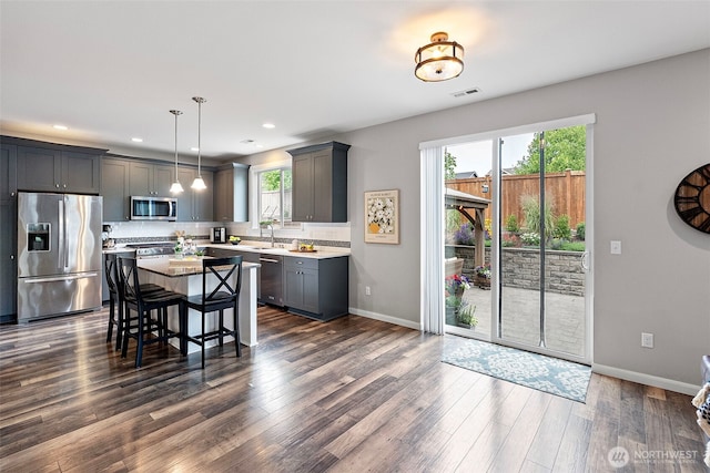 1897 Claret Loop NW, Poulsbo, WA 98370 - kitchen featuring appliances with stainless steel finishes, dark wood finished floors, a kitchen bar, recessed lighting, and pendant lighting