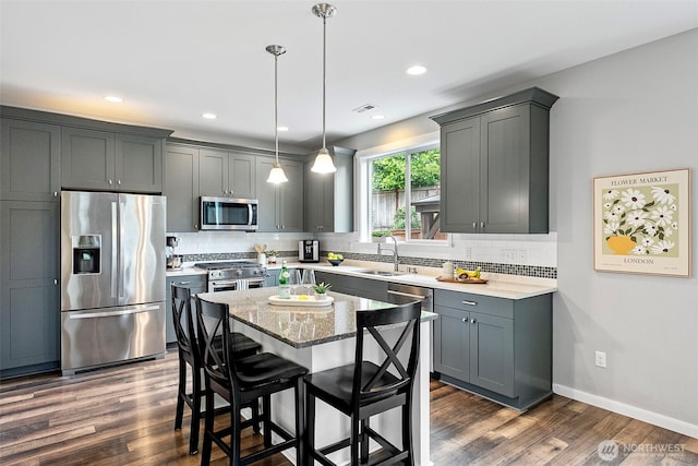 1897 Claret Loop NW, Poulsbo, WA 98370 - kitchen featuring appliances with stainless steel finishes, dark wood-style flooring, tasteful backsplash, light stone counters, and decorative light fixtures