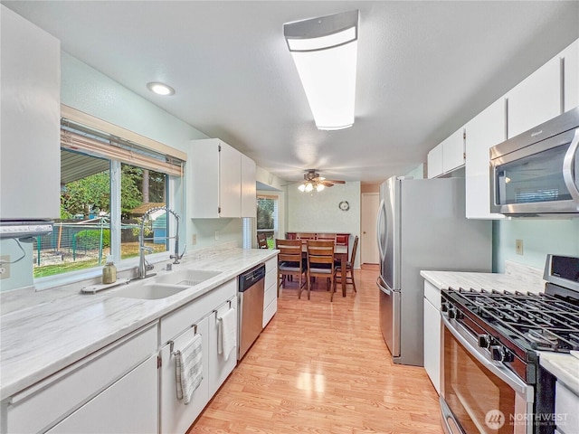 11411 208th Ave E, Bonney Lake, WA 98391 - kitchen with stainless steel appliances, light wood-type flooring, ceiling fan, and white cabinets