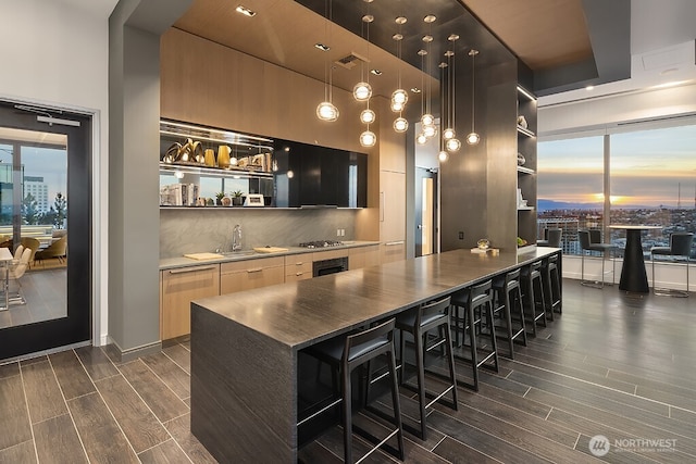 1808 Minor Ave Unit 3005, Seattle, WA 98101 - indoor wet bar featuring dark wood finished floors, decorative backsplash, stainless steel gas cooktop, and hanging light fixtures