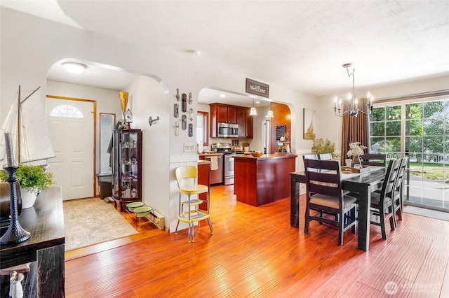 407 Offut Dr, Moses Lake, WA 98837 - dining space with arched walkways, light wood finished floors, and a chandelier