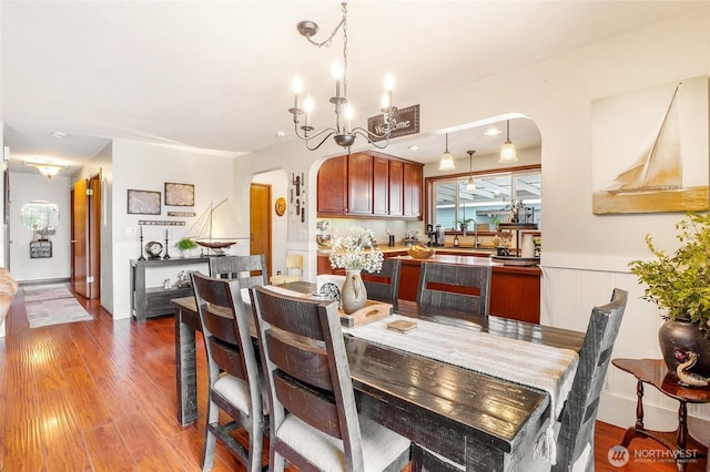 407 Offut Dr, Moses Lake, WA 98837 - dining area with arched walkways, light wood-style floors, a chandelier, and wainscoting