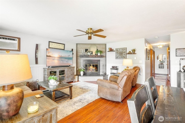 407 Offut Dr, Moses Lake, WA 98837 - living area featuring ceiling fan, a wall unit AC, wood finished floors, a fireplace, and a wainscoted wall