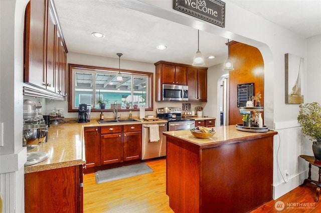 407 Offut Dr, Moses Lake, WA 98837 - kitchen with stainless steel appliances, arched walkways, hanging light fixtures, light wood finished floors, and recessed lighting