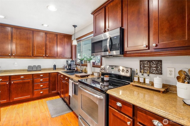 407 Offut Dr, Moses Lake, WA 98837 - kitchen featuring appliances with stainless steel finishes, light wood finished floors, hanging light fixtures, recessed lighting, and dark brown cabinets