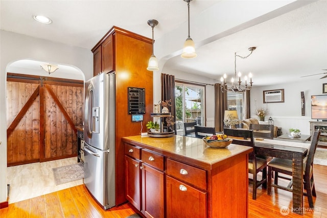 407 Offut Dr, Moses Lake, WA 98837 - kitchen with stainless steel fridge with ice dispenser, arched walkways, light wood-style floors, open floor plan, and a peninsula