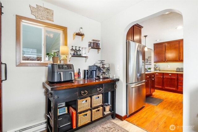 407 Offut Dr, Moses Lake, WA 98837 - kitchen featuring stainless steel fridge with ice dispenser, arched walkways, a baseboard heating unit, and light wood-style floors