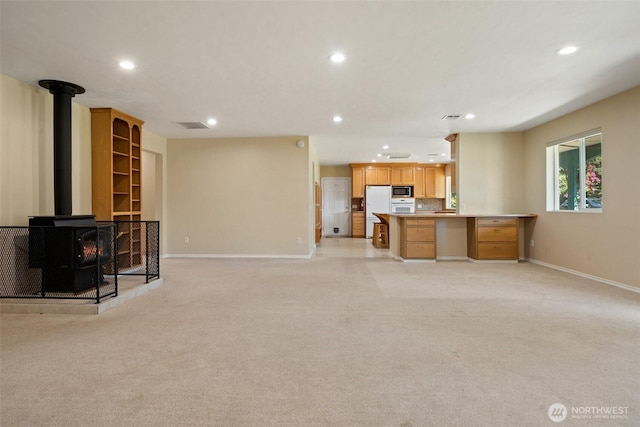 61 Cricket Ln, Sequim, WA 98382 - unfurnished living room with recessed lighting, a wood stove, and light colored carpet