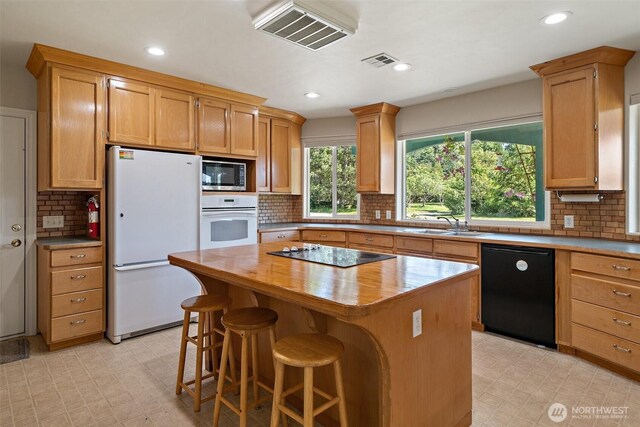 61 Cricket Ln, Sequim, WA 98382 - kitchen featuring black appliances, tasteful backsplash, a kitchen island, recessed lighting, and a breakfast bar area