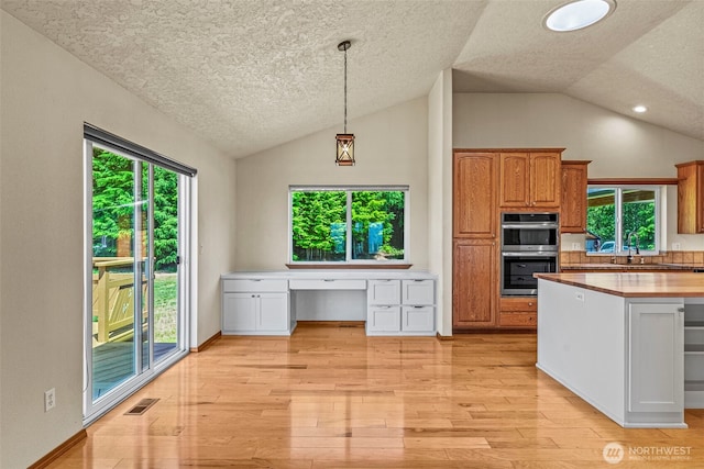 874 W State Route 4, Cathlamet, WA 98612 - kitchen with double oven, lofted ceiling, a textured ceiling, built in study area, and light wood finished floors