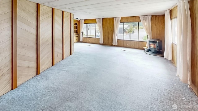 11453 Bayview Edison Rd Unit 25, Mount Vernon, WA 98273 - spare room featuring a wood stove, healthy amount of natural light, carpet floors, and wood walls