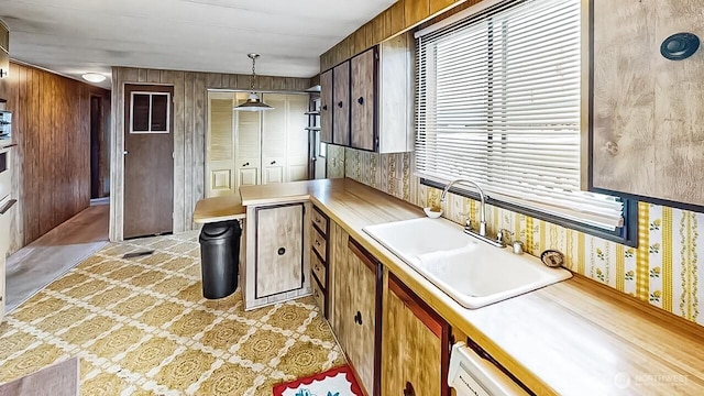 11453 Bayview Edison Rd Unit 25, Mount Vernon, WA 98273 - kitchen with light countertops, wallpapered walls, hanging light fixtures, brown cabinets, and a peninsula