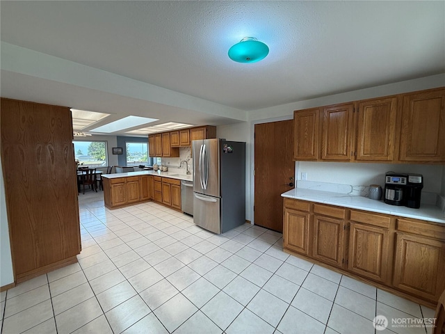 440 W Nelson Rd, Sequim, WA 98382 - kitchen with appliances with stainless steel finishes, brown cabinetry, light countertops, a peninsula, and light tile patterned flooring