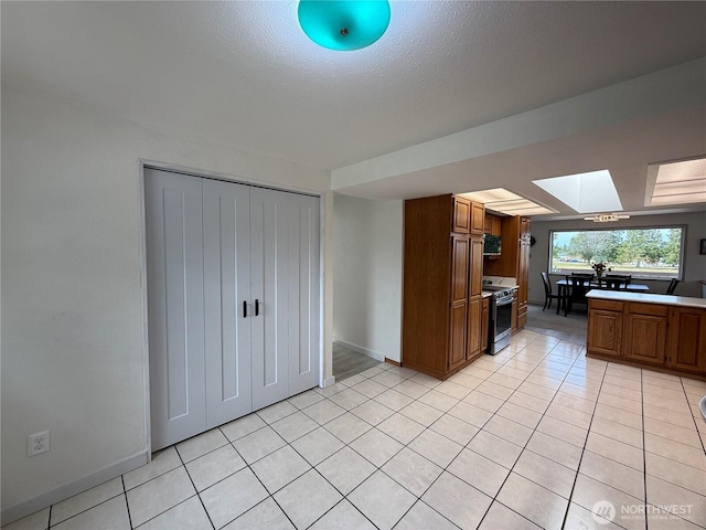 440 W Nelson Rd, Sequim, WA 98382 - kitchen with stainless steel electric stove, light tile patterned floors, brown cabinetry, light countertops, and a skylight