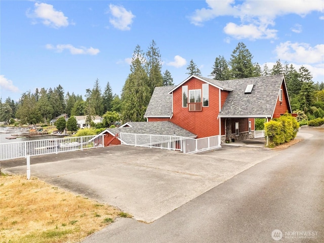 2519 Carpenter Rd, Lacey, WA 98503 - view of home's exterior with a shingled roof, driveway, stone siding, and view of scattered trees