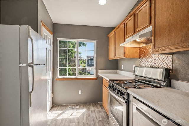 16411 156th St SE, Monroe, WA 98272 - kitchen with stainless steel appliances, under cabinet range hood, light wood-style floors, light countertops, and brown cabinets