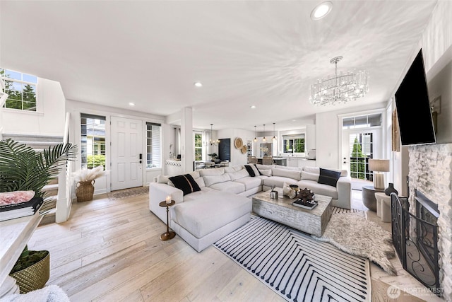 2166 NE Morgan Ln, Issaquah, WA 98029 - living room featuring a chandelier, plenty of natural light, a stone fireplace, light wood finished floors, and recessed lighting