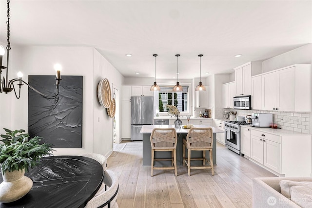 2166 NE Morgan Ln, Issaquah, WA 98029 - kitchen featuring appliances with stainless steel finishes, tasteful backsplash, white cabinetry, a center island, and light wood-type flooring