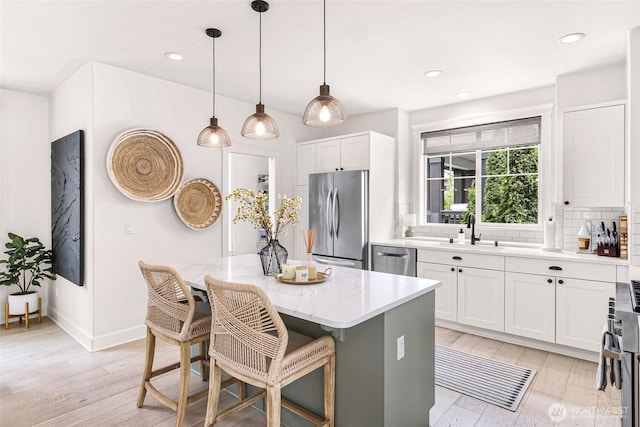 2166 NE Morgan Ln, Issaquah, WA 98029 - kitchen with stainless steel appliances, decorative backsplash, a center island, light stone counters, and light wood-style floors