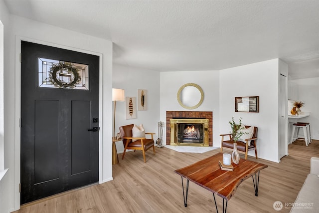 7040 SE Truman St, Port Orchard, WA 98366 - foyer entrance featuring light wood-type flooring, a brick fireplace, and a textured ceiling