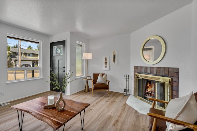 7040 SE Truman St, Port Orchard, WA 98366 - living area with light wood-style flooring, a brick fireplace, and a textured ceiling