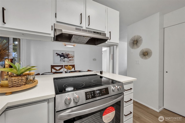 7040 SE Truman St, Port Orchard, WA 98366 - kitchen featuring under cabinet range hood, stainless steel range with electric cooktop, light countertops, light wood-style floors, and white cabinets