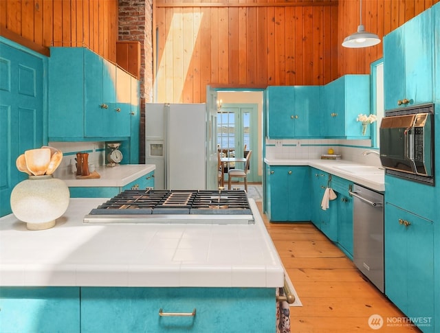 14504 Glen Acres Rd, Vashon, WA 98070 - kitchen with appliances with stainless steel finishes, wood walls, blue cabinetry, french doors, and light wood-type flooring