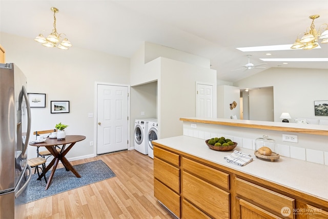 8537 Thuja Ave SE, Yelm, WA 98597 - kitchen with freestanding refrigerator, washing machine and clothes dryer, a chandelier, vaulted ceiling, and light countertops