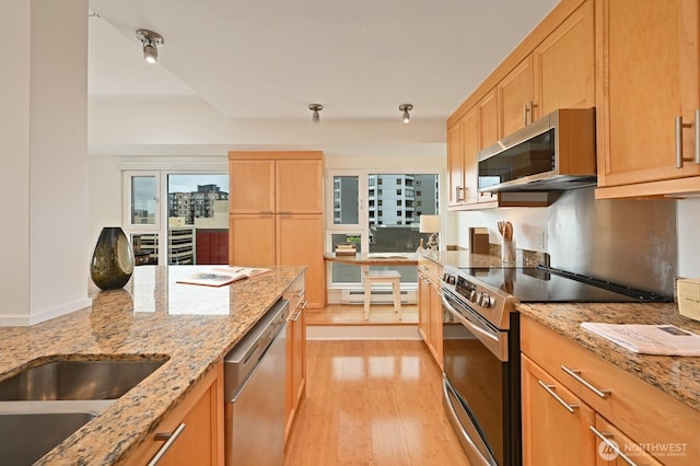 121 Vine St Unit 703, Seattle, WA 98121 - kitchen featuring stainless steel appliances, a baseboard heating unit, light wood-style flooring, light brown cabinets, and light stone countertops