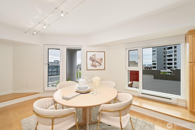 121 Vine St Unit 703, Seattle, WA 98121 - dining space featuring baseboard heating, wood finished floors, and track lighting