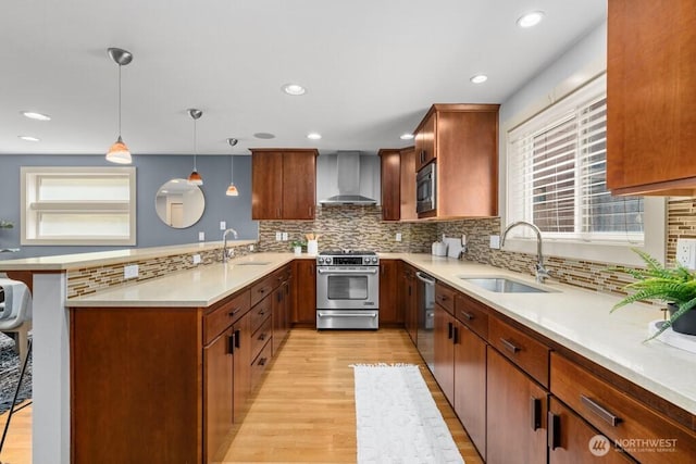 7747 Sand Point Way NE Unit A, Seattle, WA 98115 - kitchen with stainless steel appliances, wall chimney range hood, a peninsula, light countertops, and light wood-style flooring