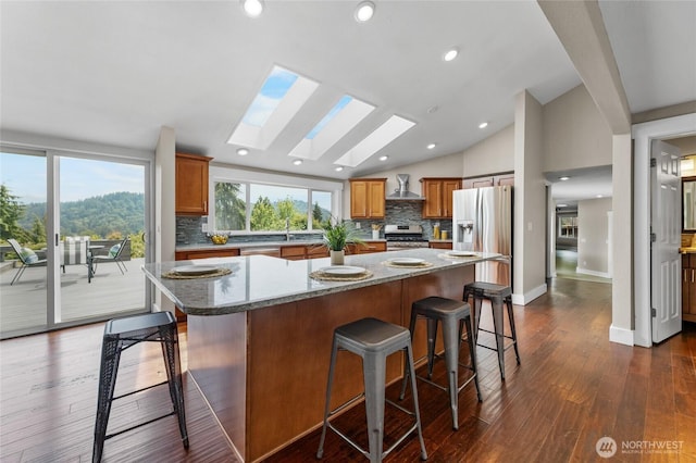 12712 232nd Ave E, Buckley, WA 98321 - kitchen with stainless steel appliances, decorative backsplash, vaulted ceiling, wall chimney exhaust hood, and a center island