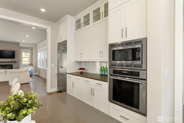 8784 NE Winslow Grove Ct, Bainbridge Island, WA 98110 - kitchen featuring stainless steel appliances, dark wood-type flooring, glass insert cabinets, tasteful backsplash, and open floor plan