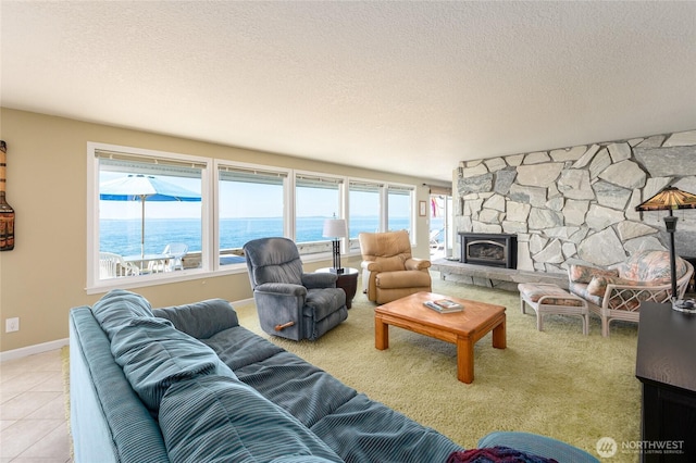 1523 N Whitecap Ln, Oak Harbor, WA 98277 - living area featuring a textured ceiling, a water view, a stone fireplace, and tile patterned floors