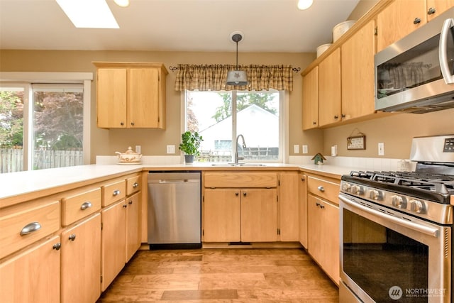 5117 77th St E, Tacoma, WA 98443 - kitchen featuring stainless steel appliances, light brown cabinets, a skylight, light wood finished floors, and light countertops