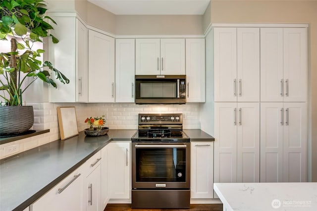 3116 164th St SW Unit 806, Lynnwood, WA 98087 - kitchen featuring appliances with stainless steel finishes, white cabinetry, backsplash, and dark countertops